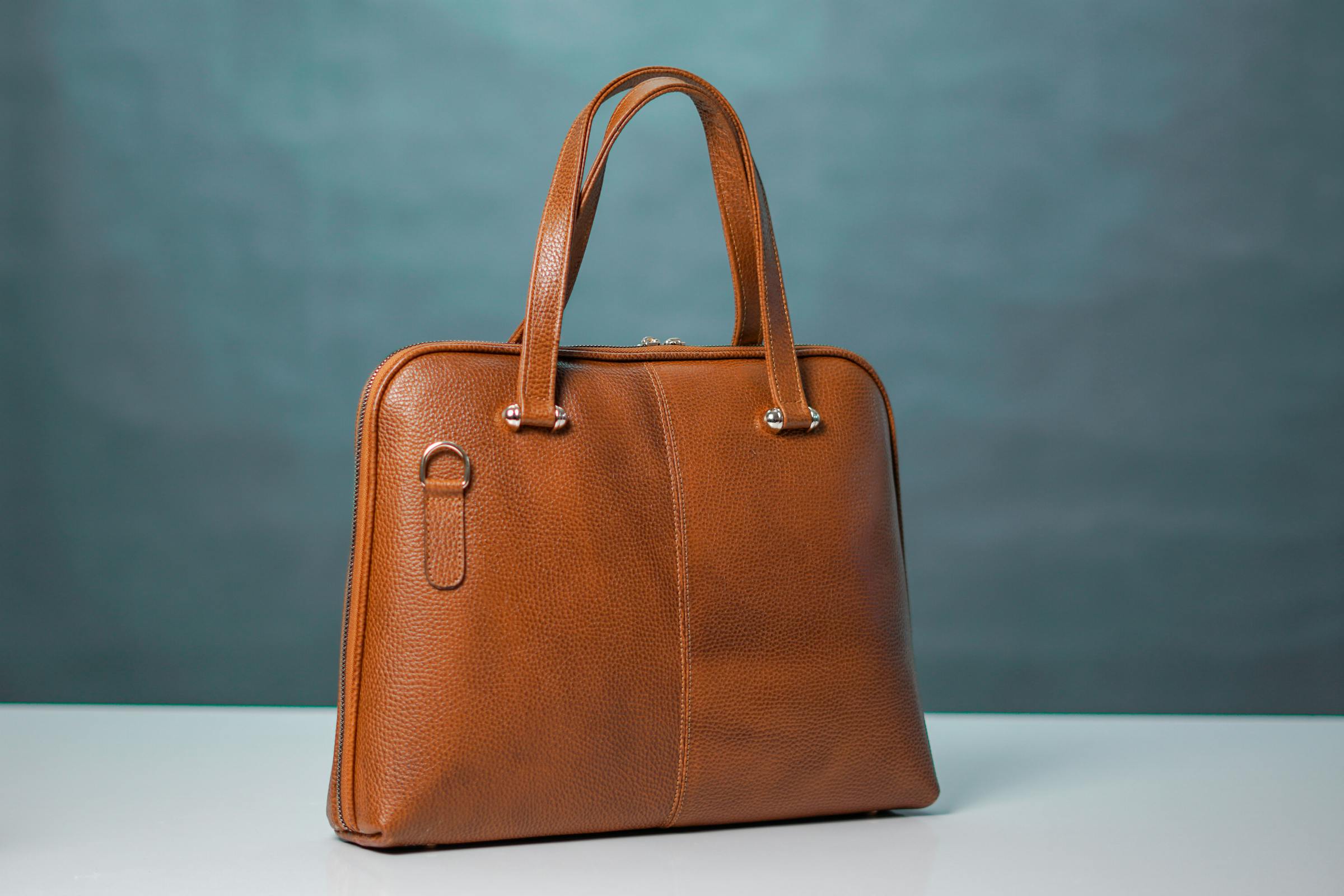 A finely made leather handbag photographed against a quiet, neutral background.